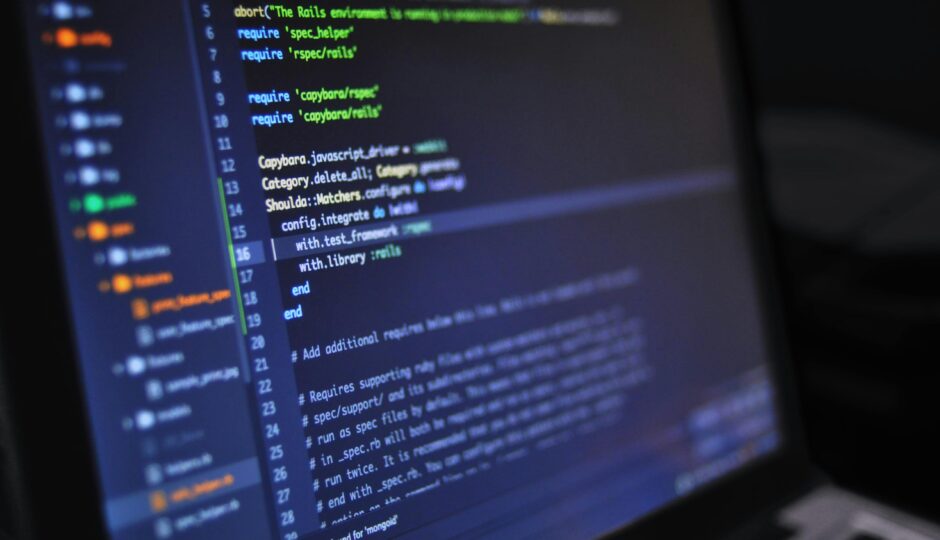 Close-up of a computer screen displaying programming code in a dark environment.